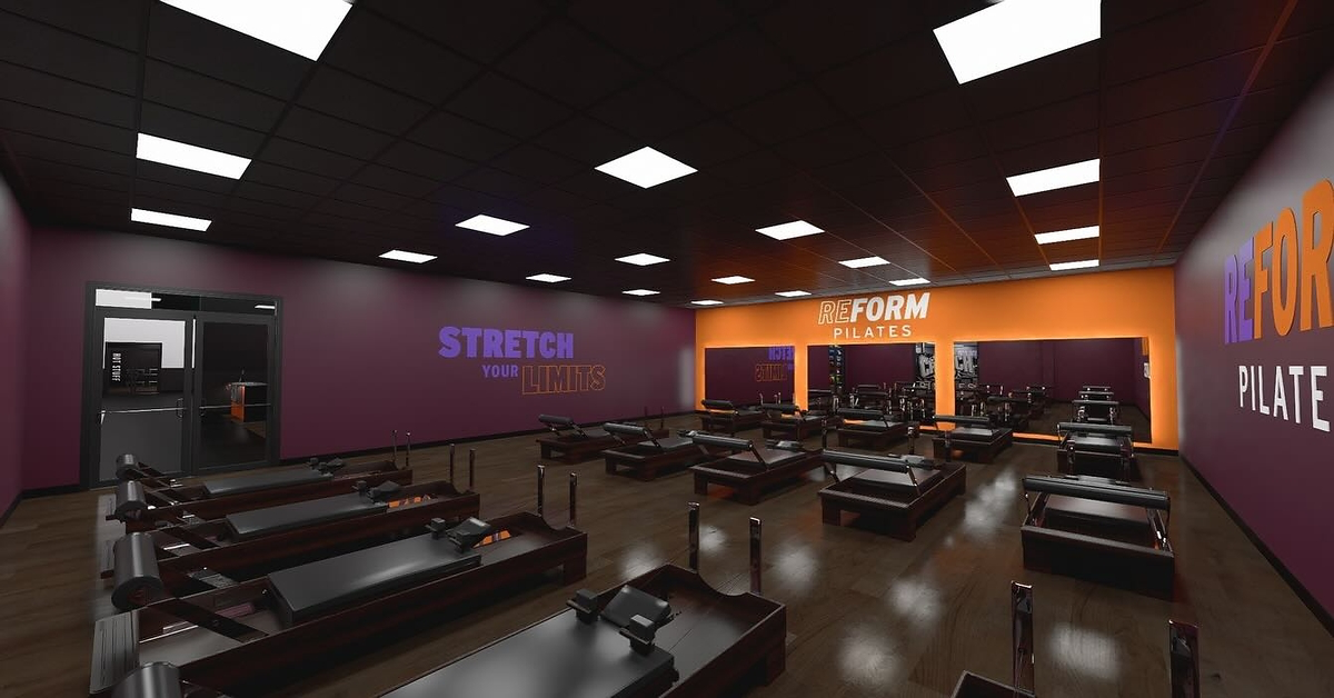 Reformer Pilates equipment lined up inside a modern fitness club studio